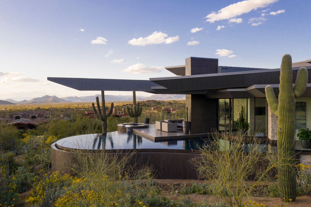 Photo of an expansive modern detached house in Phoenix with stone cladding, a butterfly roof and a metal roof.
