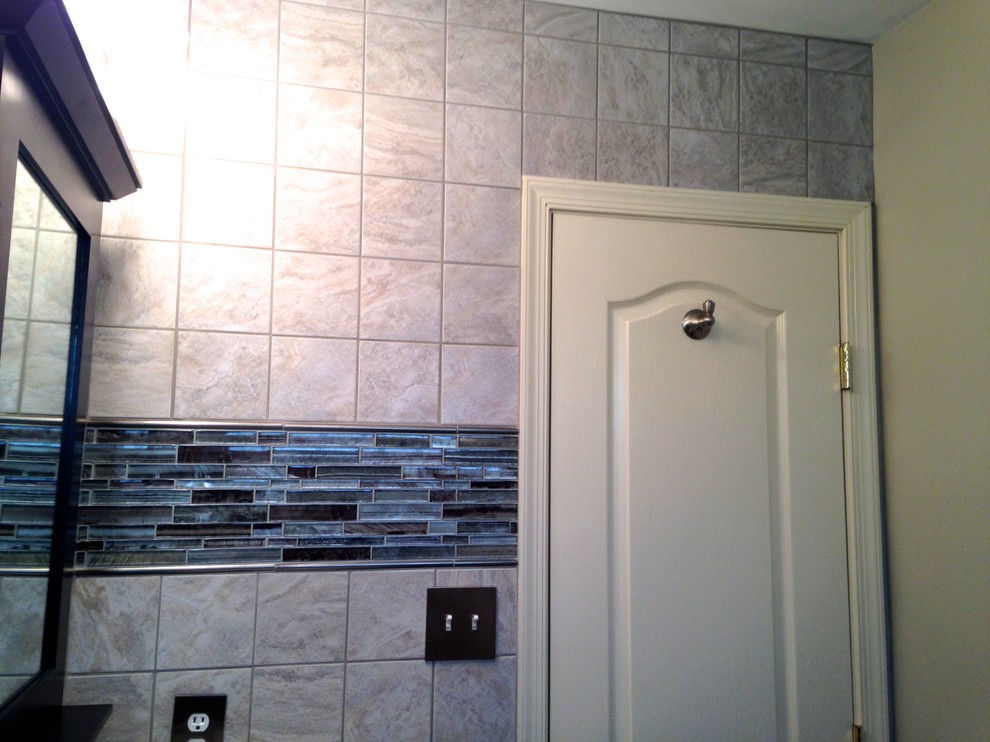 Photo of a small transitional 3/4 bathroom in Other with an integrated sink, recessed-panel cabinets, dark wood cabinets, solid surface benchtops, an alcove tub, a shower/bathtub combo, a two-piece toilet, gray tile, porcelain tile, blue walls and ceramic floors.