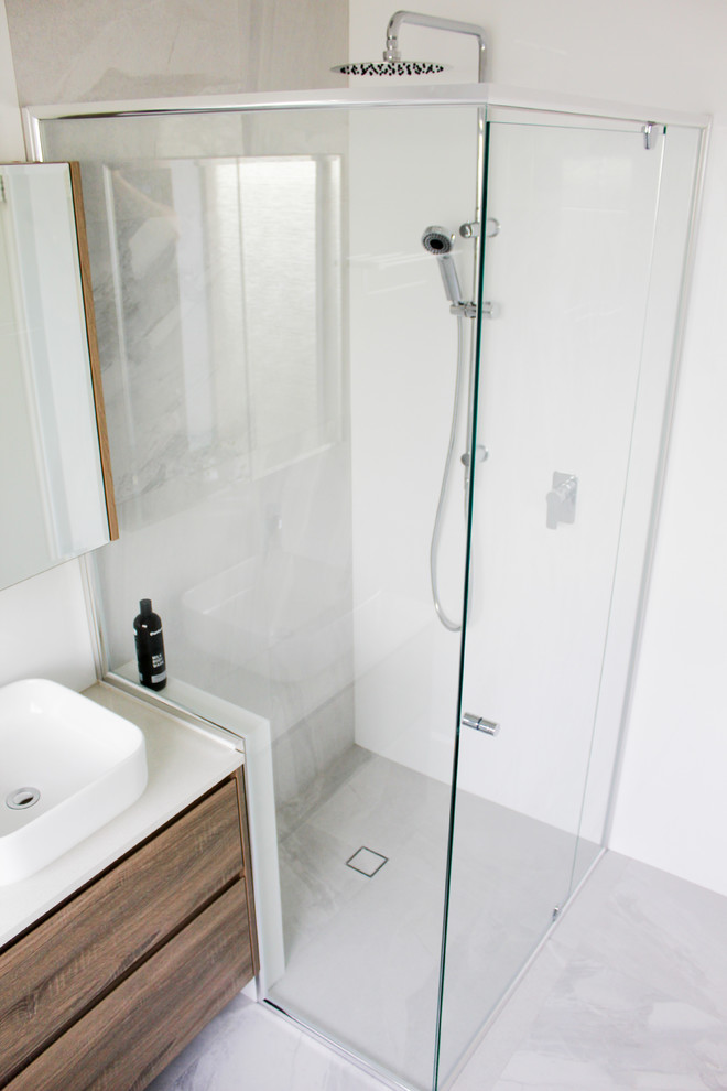 Inspiration for a mid-sized modern kids bathroom in Perth with flat-panel cabinets, brown cabinets, a drop-in tub, a corner shower, white tile, ceramic tile, white walls, porcelain floors, a vessel sink, engineered quartz benchtops, grey floor, a hinged shower door and white benchtops.