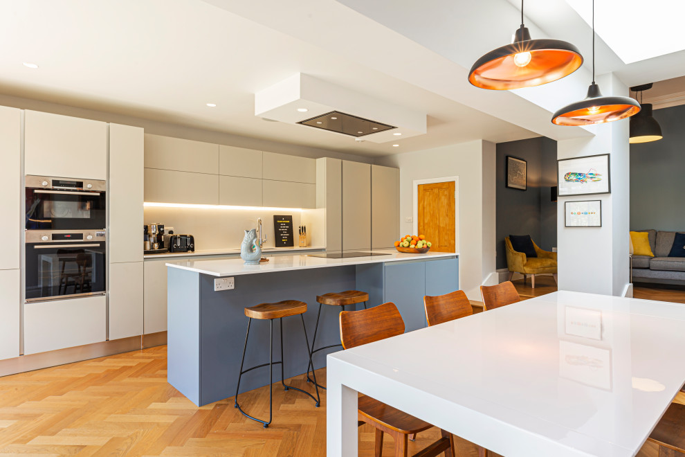 Idee per una cucina contemporanea con ante lisce, ante beige, pavimento in legno massello medio, penisola, pavimento marrone e top bianco