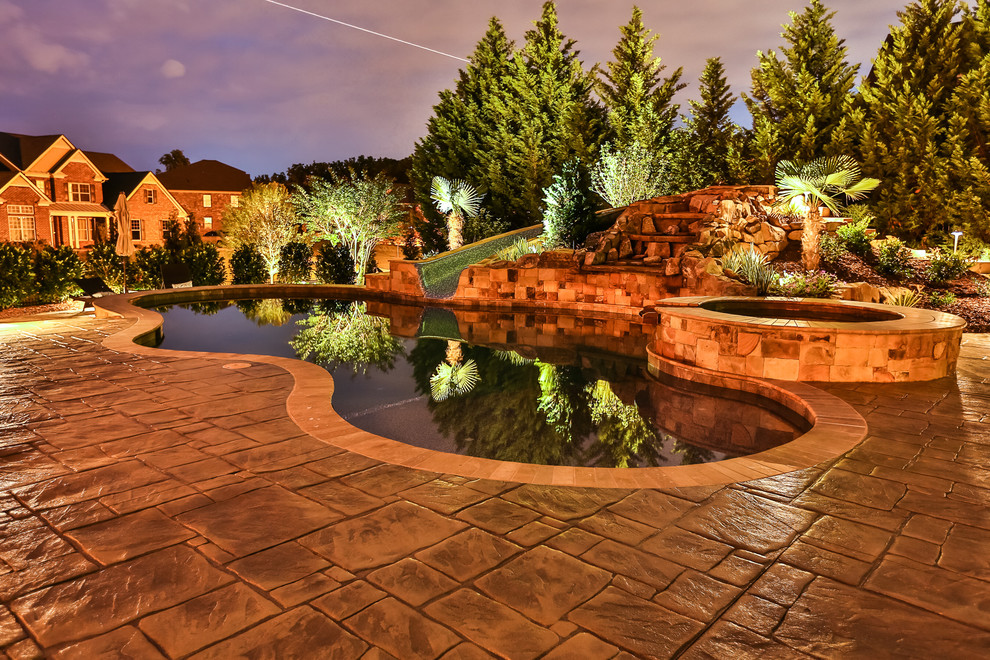 Inspiration for a large backyard custom-shaped natural pool in Atlanta with a water feature and stamped concrete.