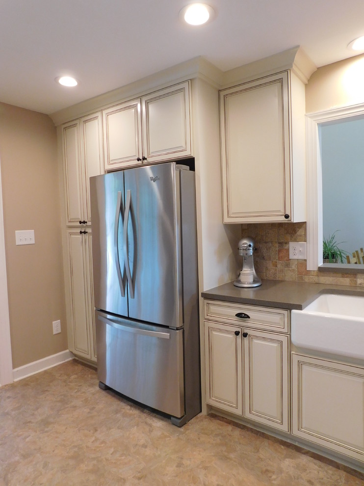 Enclosed kitchen - mid-sized transitional galley vinyl floor enclosed kitchen idea with a farmhouse sink, raised-panel cabinets, beige cabinets, solid surface countertops, multicolored backsplash, stone tile backsplash, stainless steel appliances and no island
