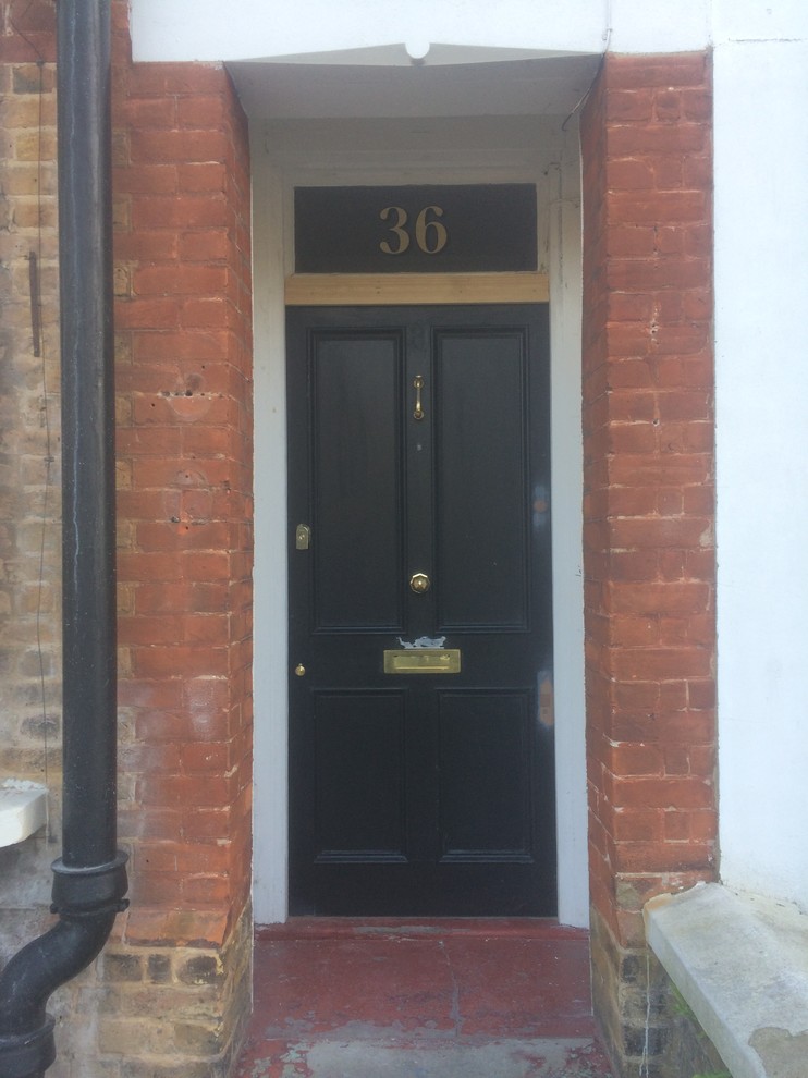 Photo of a mid-sized traditional front door in Kent with white walls, concrete floors, a single front door and a black front door.