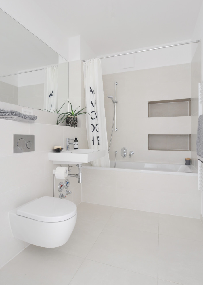 This is an example of a small contemporary 3/4 bathroom in Berlin with a drop-in tub, a shower/bathtub combo, a wall-mount toilet, beige tile, porcelain tile, white walls, porcelain floors, a wall-mount sink, beige floor and a shower curtain.