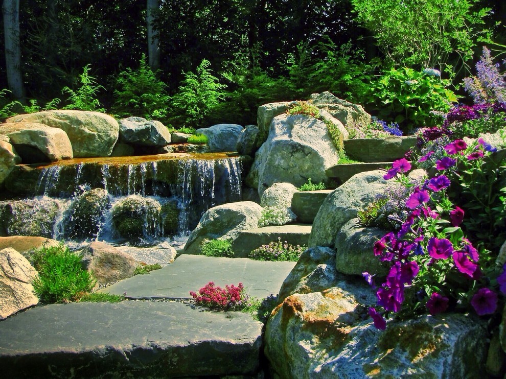 Inspiration for a mid-sized traditional backyard custom-shaped natural pool in Newark with natural stone pavers.