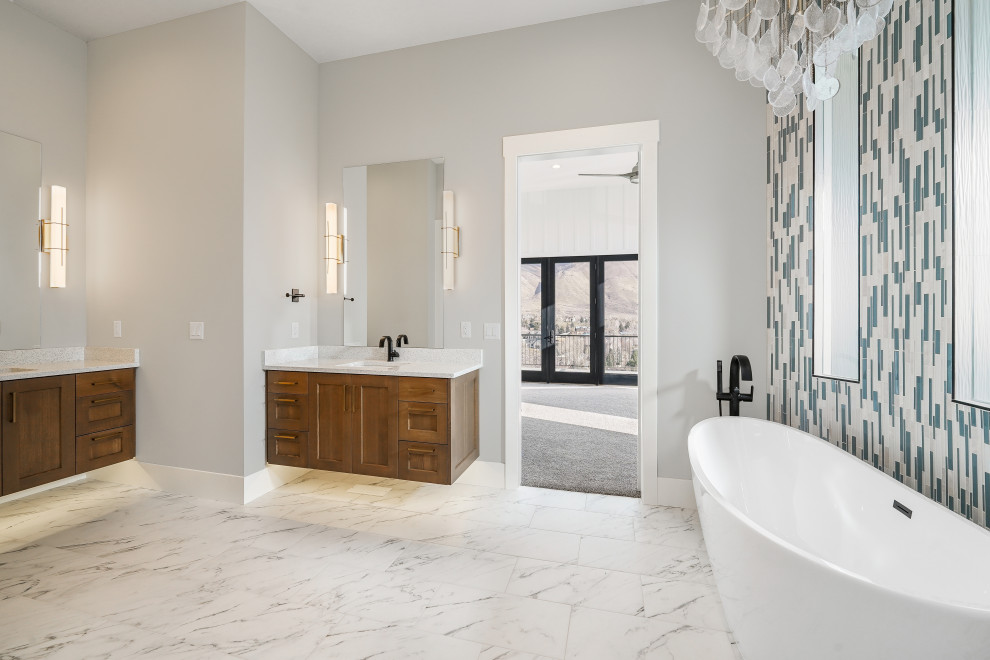 This is an example of a large modern ensuite bathroom in Salt Lake City with shaker cabinets, brown cabinets, a freestanding bath, a walk-in shower, a two-piece toilet, blue tiles, glass tiles, grey walls, porcelain flooring, a submerged sink, engineered stone worktops, white floors, an open shower, white worktops, a laundry area, double sinks and a floating vanity unit.