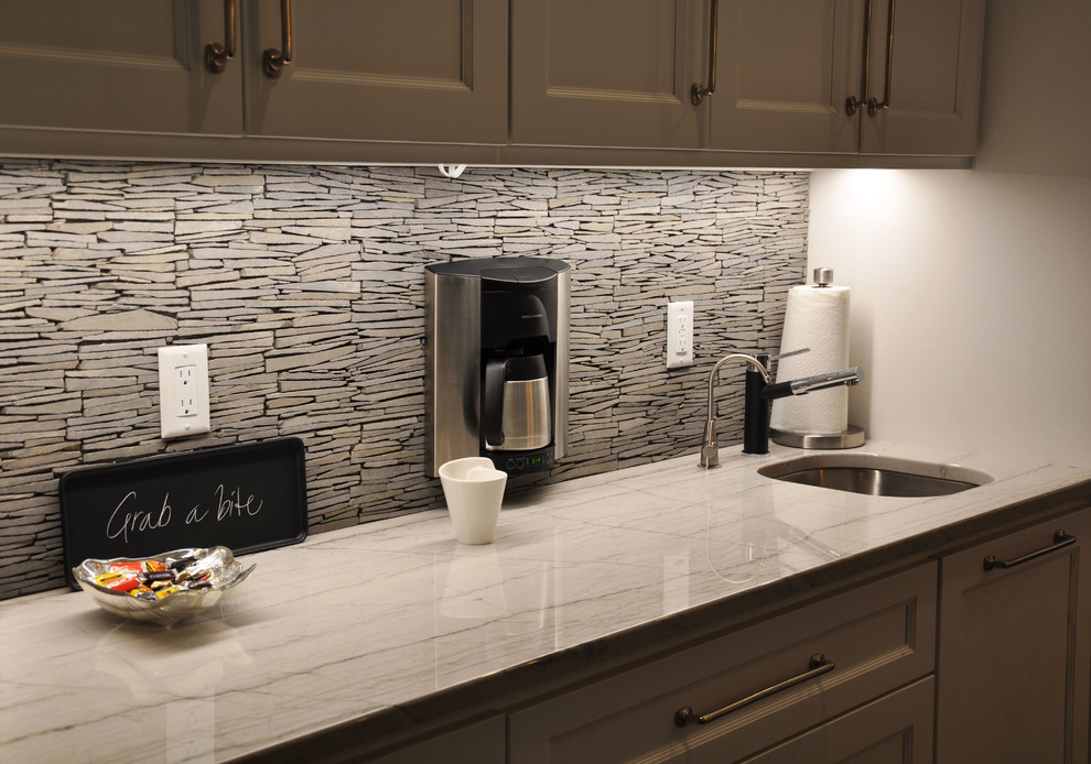 Example of a large mountain style u-shaped dark wood floor and brown floor eat-in kitchen design in Milwaukee with recessed-panel cabinets, white cabinets, granite countertops, gray backsplash, stone tile backsplash, stainless steel appliances, an island and an undermount sink