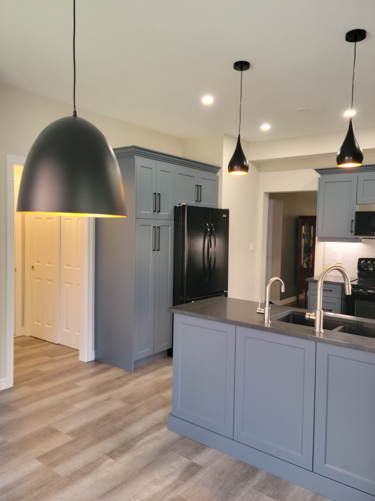 Example of a mid-sized transitional u-shaped vinyl floor eat-in kitchen design with an undermount sink, recessed-panel cabinets, blue cabinets, quartzite countertops, white backsplash, porcelain backsplash, black appliances, a peninsula and black countertops