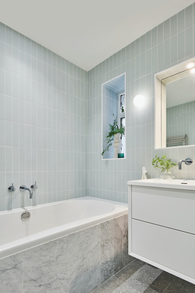Exempel på ett litet modernt vit vitt badrum för barn, med släta luckor, vita skåp, ett platsbyggt badkar, en kantlös dusch, en vägghängd toalettstol, grön kakel, porslinskakel, vita väggar, klinkergolv i porslin, ett integrerad handfat, bänkskiva i akrylsten, grått golv och dusch med skjutdörr