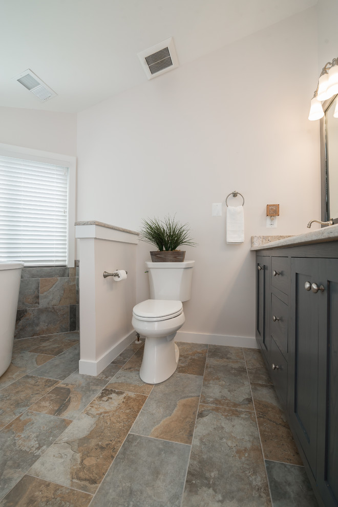 Inspiration for a mid-sized transitional master bathroom in DC Metro with shaker cabinets, grey cabinets, a corner tub, an open shower, a two-piece toilet, grey walls, travertine floors, an undermount sink and granite benchtops.