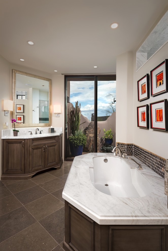 Design ideas for a mid-sized master bathroom in Phoenix with recessed-panel cabinets, medium wood cabinets, an undermount tub, brown tile, an undermount sink, glass tile and marble benchtops.