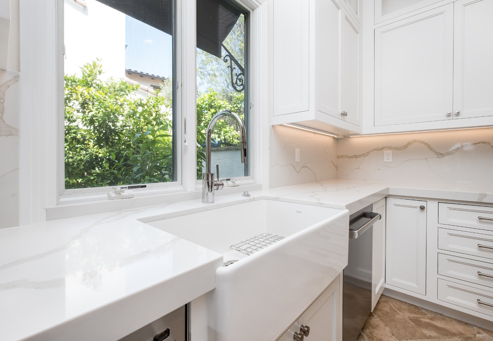 Inspiration for a mid-sized transitional l-shaped porcelain tile and beige floor enclosed kitchen remodel in Orange County with a farmhouse sink, recessed-panel cabinets, white cabinets, quartz countertops, white backsplash, marble backsplash, stainless steel appliances and an island