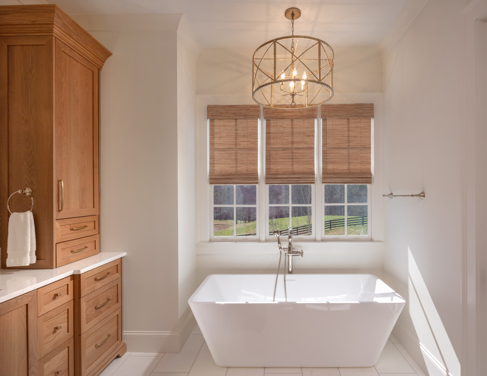 Photo of a mid-sized transitional master bathroom in Atlanta with shaker cabinets, light wood cabinets, a freestanding tub, a curbless shower, a one-piece toilet, white tile, mosaic tile, white walls, marble floors, an undermount sink, engineered quartz benchtops, white floor, a hinged shower door, white benchtops, a shower seat, a double vanity and a built-in vanity.