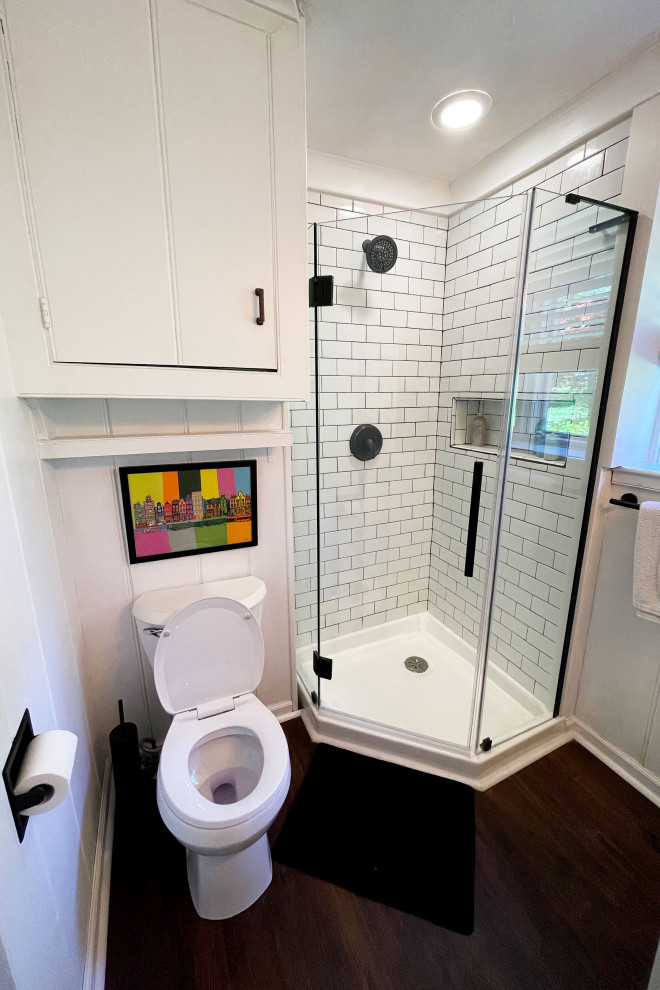 Lantlig inredning av ett litet badrum med dusch, med skåp i shakerstil, vita skåp, en hörndusch, en toalettstol med separat cisternkåpa, vit kakel, keramikplattor, vita väggar, laminatgolv, ett nedsänkt handfat, bänkskiva i akrylsten, brunt golv och dusch med gångjärnsdörr