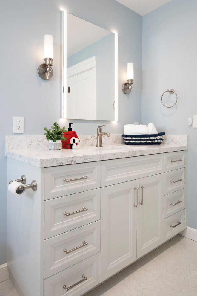 Cette image montre un WC et toilettes craftsman de taille moyenne avec un placard avec porte à panneau encastré, des portes de placard blanches, WC à poser, un carrelage blanc, des carreaux de porcelaine, un mur bleu, un sol en carrelage de terre cuite, un lavabo encastré, un plan de toilette en quartz modifié, un sol blanc, un plan de toilette blanc et meuble-lavabo encastré.