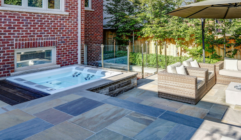Photo of a mid-sized transitional backyard rectangular pool in Toronto with with privacy feature and natural stone pavers.