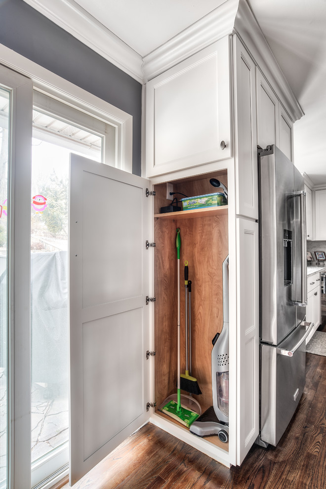 Eat-in kitchen - mid-sized traditional l-shaped dark wood floor eat-in kitchen idea in New York with an undermount sink, shaker cabinets, white cabinets, gray backsplash, stone tile backsplash, stainless steel appliances, an island and multicolored countertops