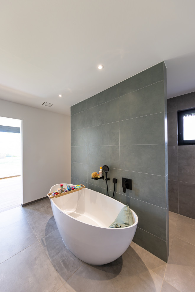 Idée de décoration pour une salle de bain principale design avec une baignoire indépendante, une douche à l'italienne, WC séparés, un mur vert, un sol marron, aucune cabine, meuble-lavabo encastré et un mur en pierre.