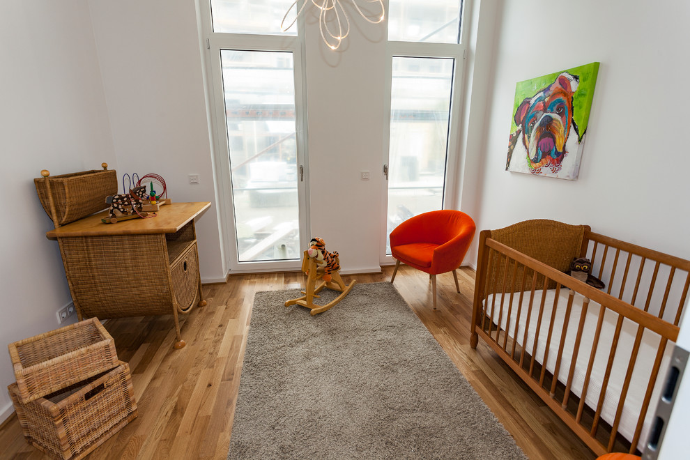 Babyzimmer With weißer Wandfarbe, braunem Holzboden and braunem Boden in Leipzig