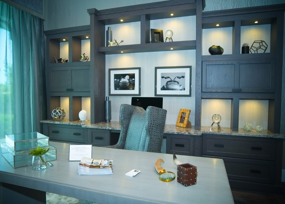 This is an example of an expansive transitional study room in Miami with grey walls, a standard fireplace, a stone fireplace surround and a freestanding desk.