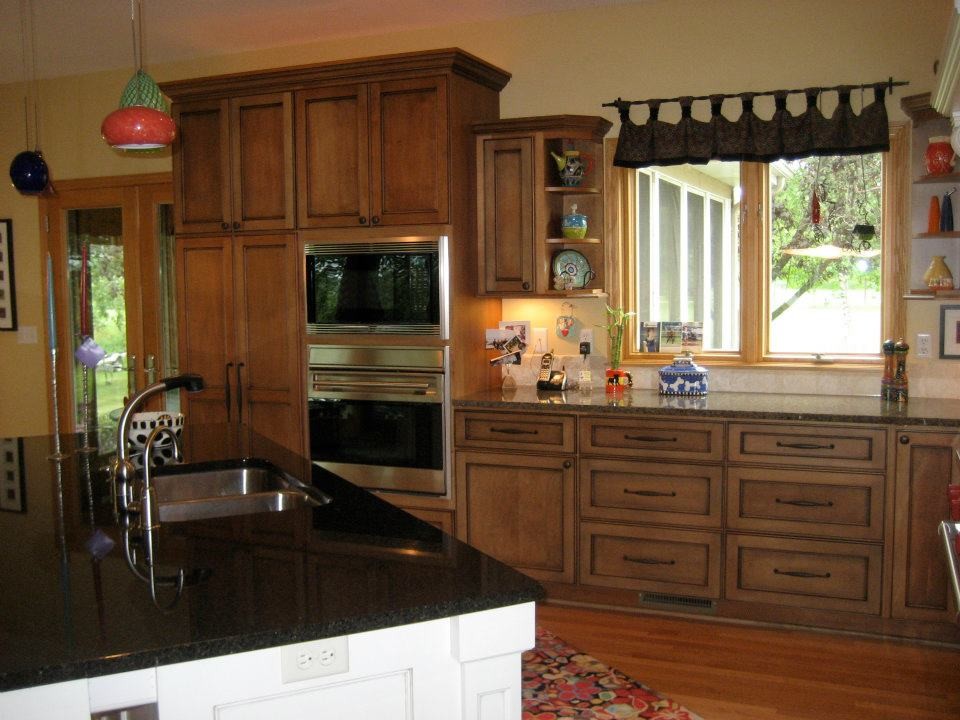 Mid-sized transitional l-shaped dark wood floor open concept kitchen photo in Milwaukee with a double-bowl sink, recessed-panel cabinets, dark wood cabinets, beige backsplash, stone tile backsplash, stainless steel appliances, an island and granite countertops
