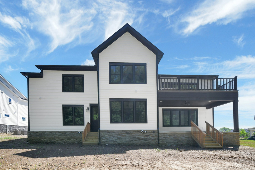 Imagen de fachada de casa blanca y negra clásica renovada de dos plantas con revestimiento de aglomerado de cemento, tejado de teja de madera y panel y listón