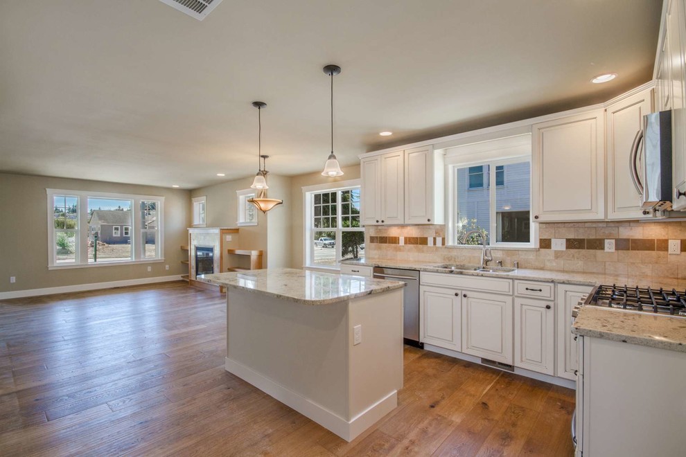 Mid-sized arts and crafts l-shaped open plan kitchen in Seattle with white cabinets, granite benchtops, beige splashback, stainless steel appliances, medium hardwood floors and with island.