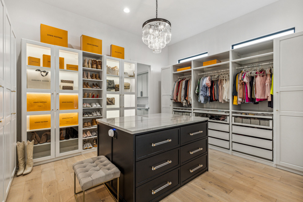 Large contemporary gender-neutral walk-in wardrobe in Dallas with glass-front cabinets, white cabinets, light hardwood floors and white floor.