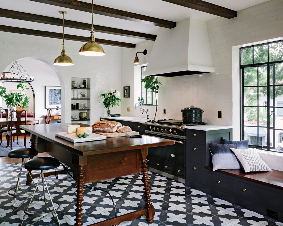 This is an example of a mediterranean kitchen in Portland with shaker cabinets, black cabinets, white splashback, subway tile splashback, black appliances, with island and ceramic floors.