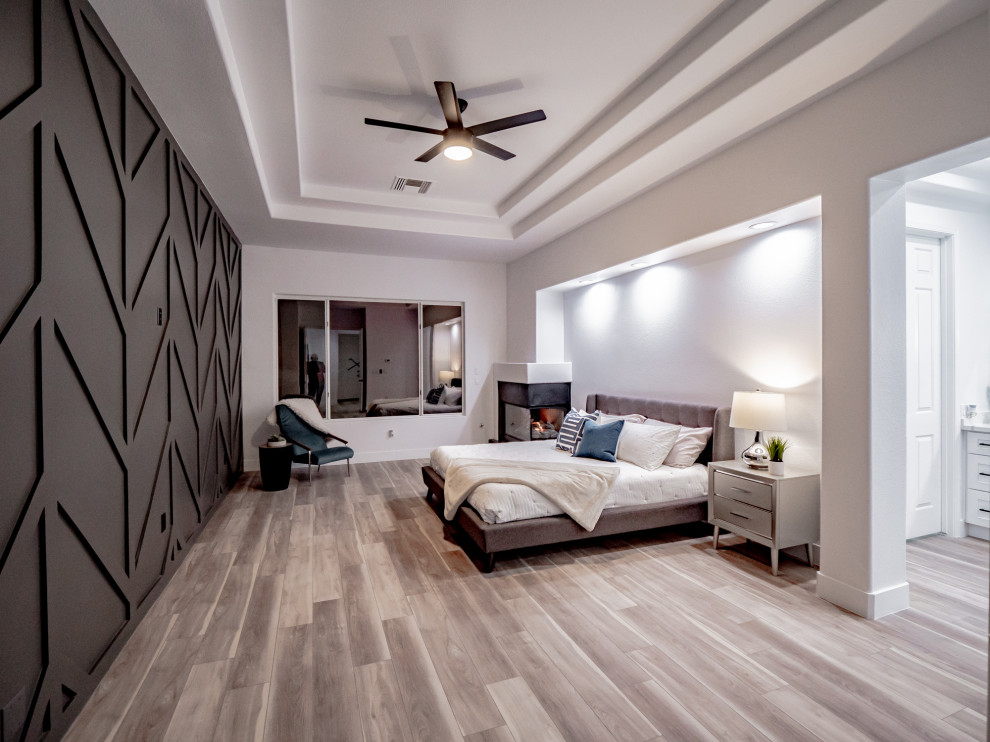 Exempel på ett modernt huvudsovrum, med en öppen hörnspis, en spiselkrans i trä, brunt golv, grå väggar och vinylgolv