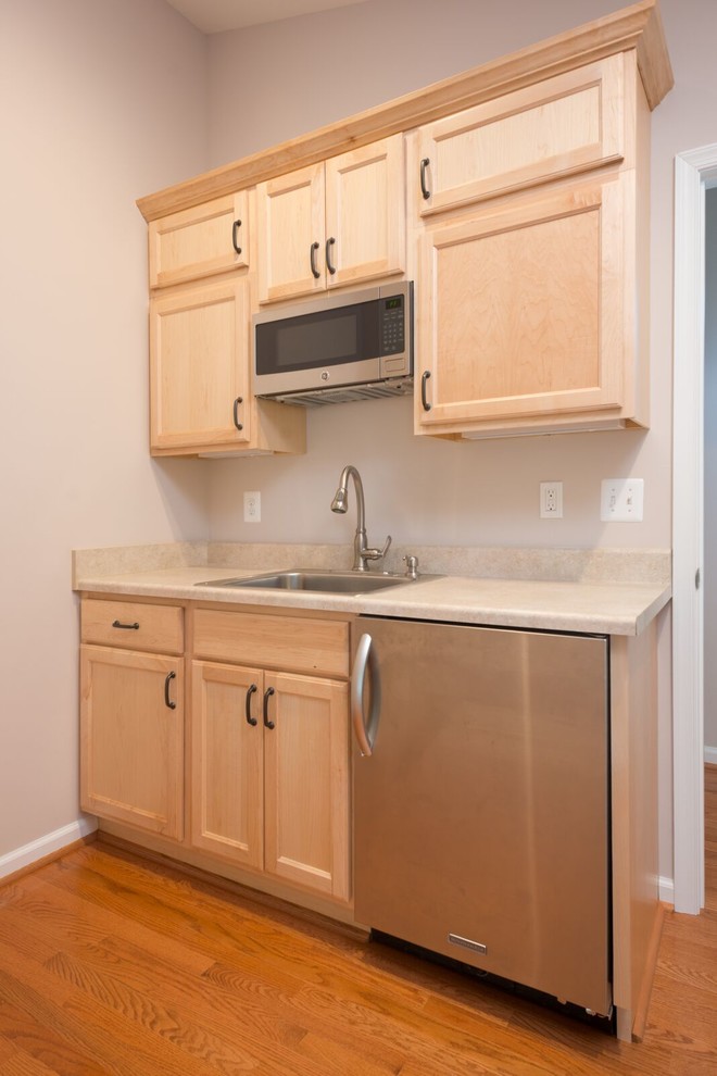 This is an example of a large traditional single-wall separate kitchen in San Francisco with a drop-in sink, recessed-panel cabinets, light wood cabinets, laminate benchtops, stainless steel appliances, no island, brown floor, dark hardwood floors and beige benchtop.