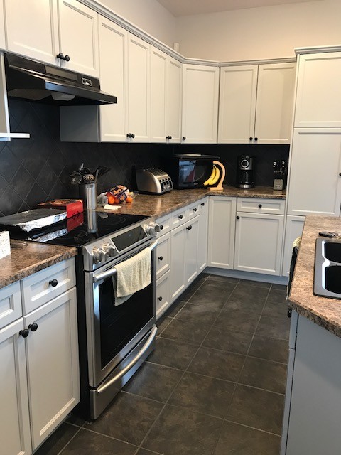 Mid-sized transitional u-shaped ceramic tile enclosed kitchen photo in Edmonton with a drop-in sink, shaker cabinets, white cabinets, granite countertops, gray backsplash, ceramic backsplash, stainless steel appliances and an island