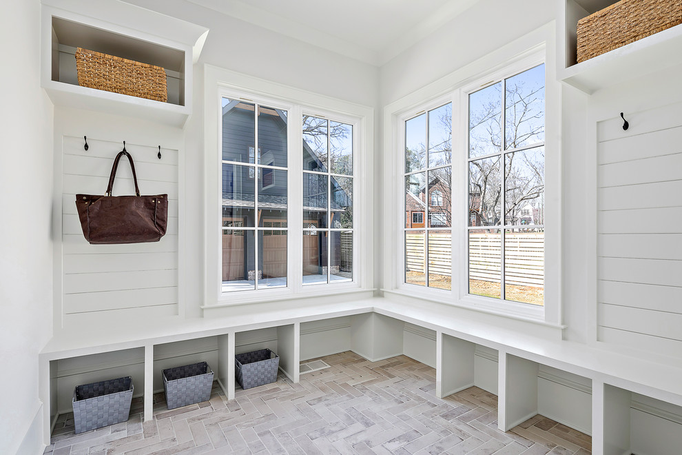 Design ideas for a mid-sized country mudroom in Charlotte with beige walls, brick floors and beige floor.