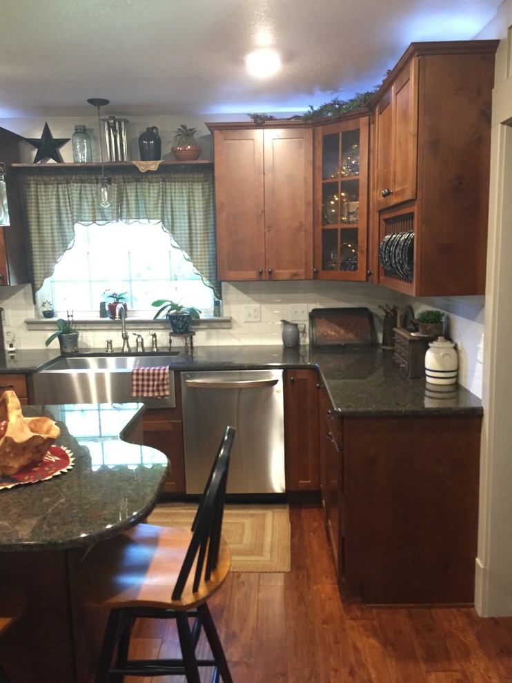 Enclosed kitchen - mid-sized transitional u-shaped enclosed kitchen idea with a farmhouse sink, shaker cabinets, medium tone wood cabinets, granite countertops, white backsplash, stainless steel appliances and an island