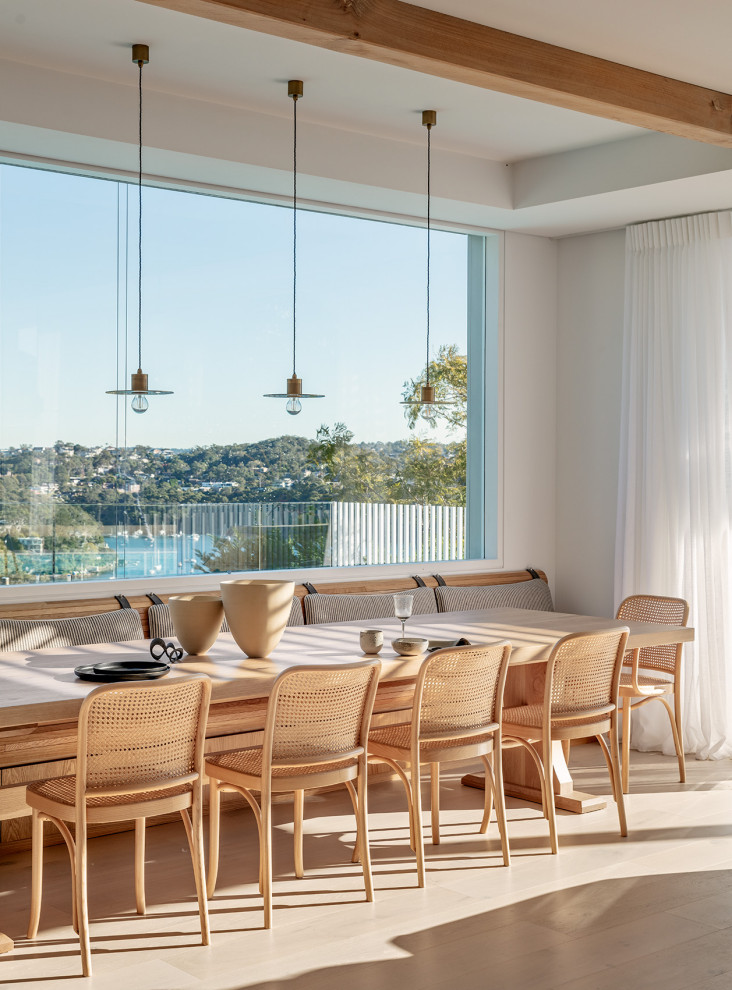 Photo of a large contemporary open plan dining in Sydney with white walls, light hardwood floors and exposed beam.