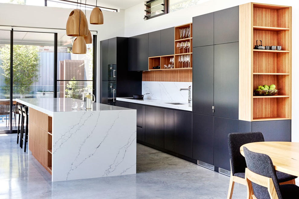 Inspiration for a small contemporary single-wall eat-in kitchen in Sydney with an undermount sink, flat-panel cabinets, black cabinets, concrete floors, with island, white splashback, black appliances, quartz benchtops, stone slab splashback, grey floor and white benchtop.