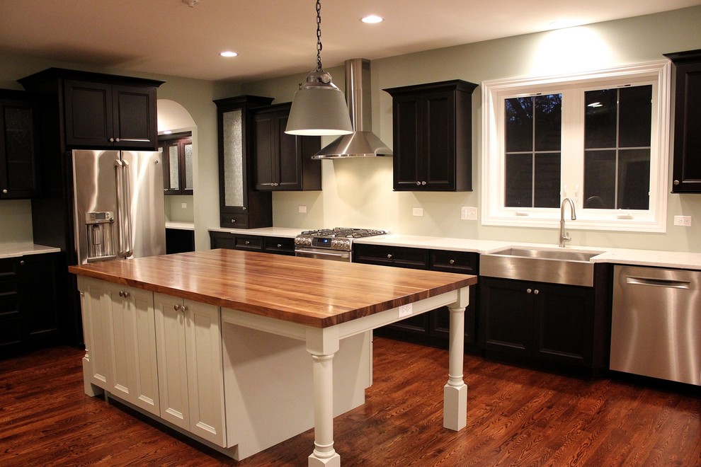 Inspiration for a mid-sized transitional single-wall dark wood floor enclosed kitchen remodel in Chicago with an undermount sink, recessed-panel cabinets, white cabinets, solid surface countertops, white backsplash, porcelain backsplash, stainless steel appliances and an island