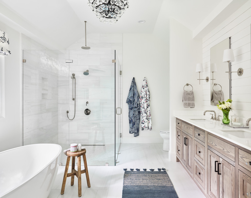 Photo of a beach style master bathroom in Boston with light wood cabinets, a freestanding tub, a curbless shower, white tile, white walls, an undermount sink, white floor, a hinged shower door and white benchtops.