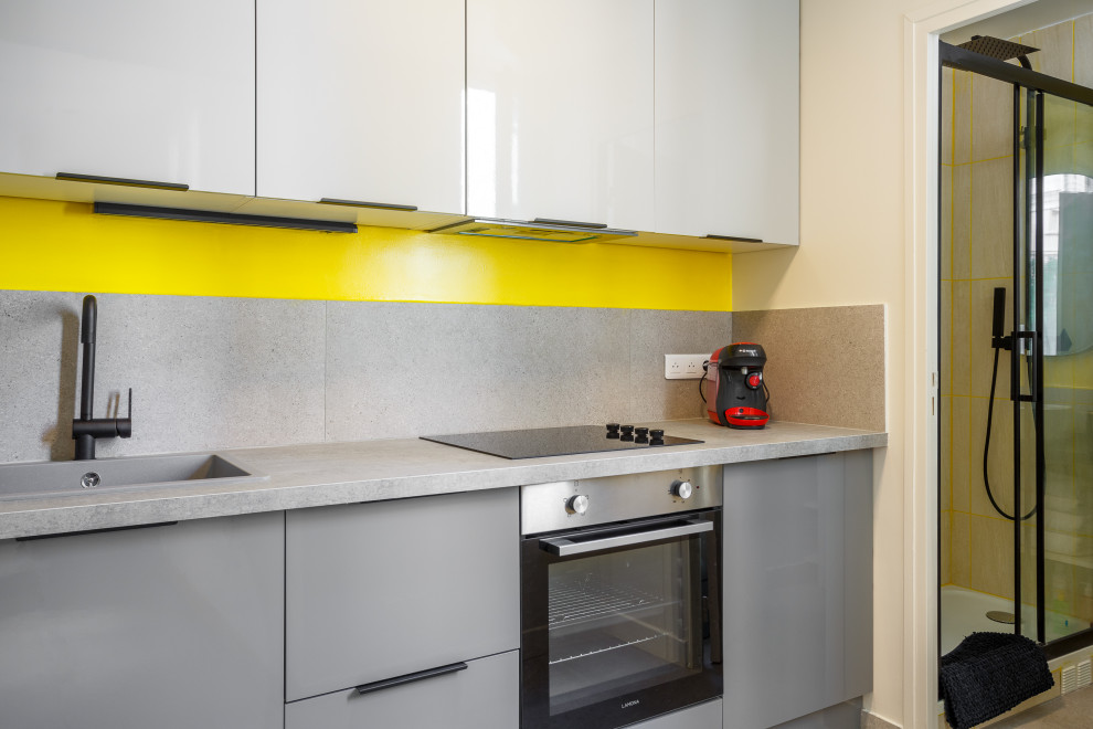 This is an example of a tropical open plan kitchen in Paris with a single-bowl sink, beaded inset cabinets, wood benchtops, yellow splashback, stone slab splashback, stainless steel appliances, cement tiles, grey floor and grey benchtop.