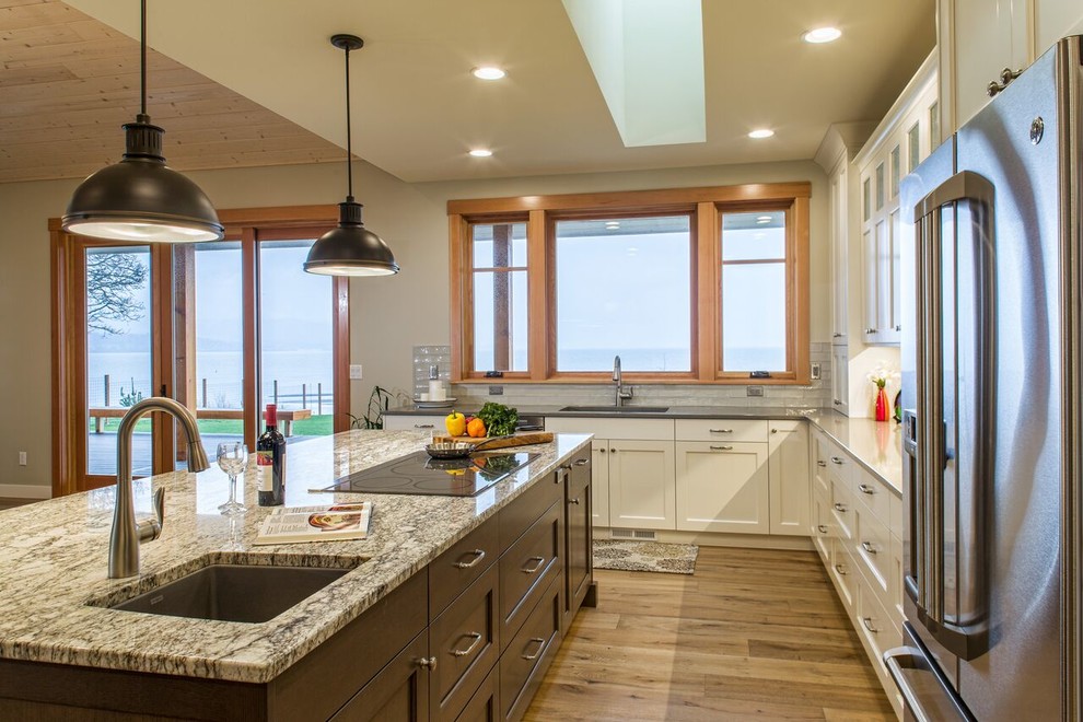 Example of a large transitional medium tone wood floor kitchen design in Seattle with shaker cabinets, white cabinets, granite countertops, an island, an undermount sink, white backsplash, subway tile backsplash and stainless steel appliances