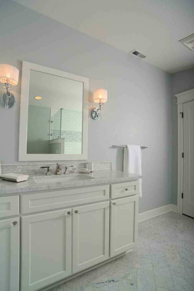 This is an example of a mid-sized traditional 3/4 bathroom in Seattle with a corner shower, gray tile, ceramic floors, white floor, a hinged shower door, recessed-panel cabinets, white cabinets, grey walls, an undermount sink, marble benchtops and white benchtops.