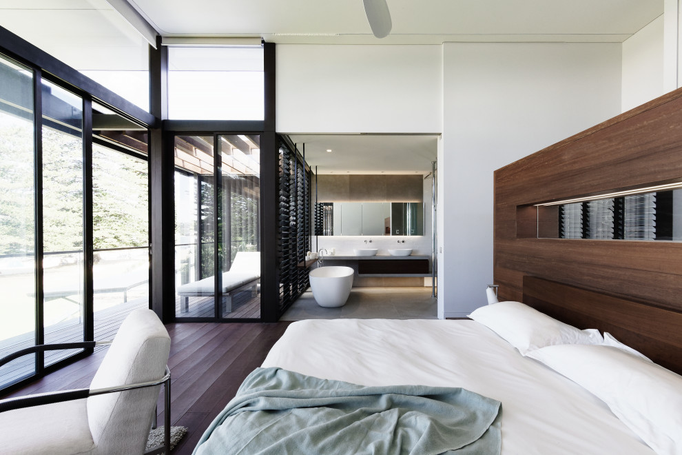 Design ideas for a large contemporary master bedroom in Central Coast with white walls, dark hardwood floors and brown floor.