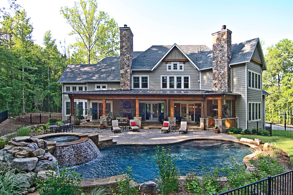 This is an example of a large country backyard custom-shaped natural pool in Charlotte with a hot tub and natural stone pavers.