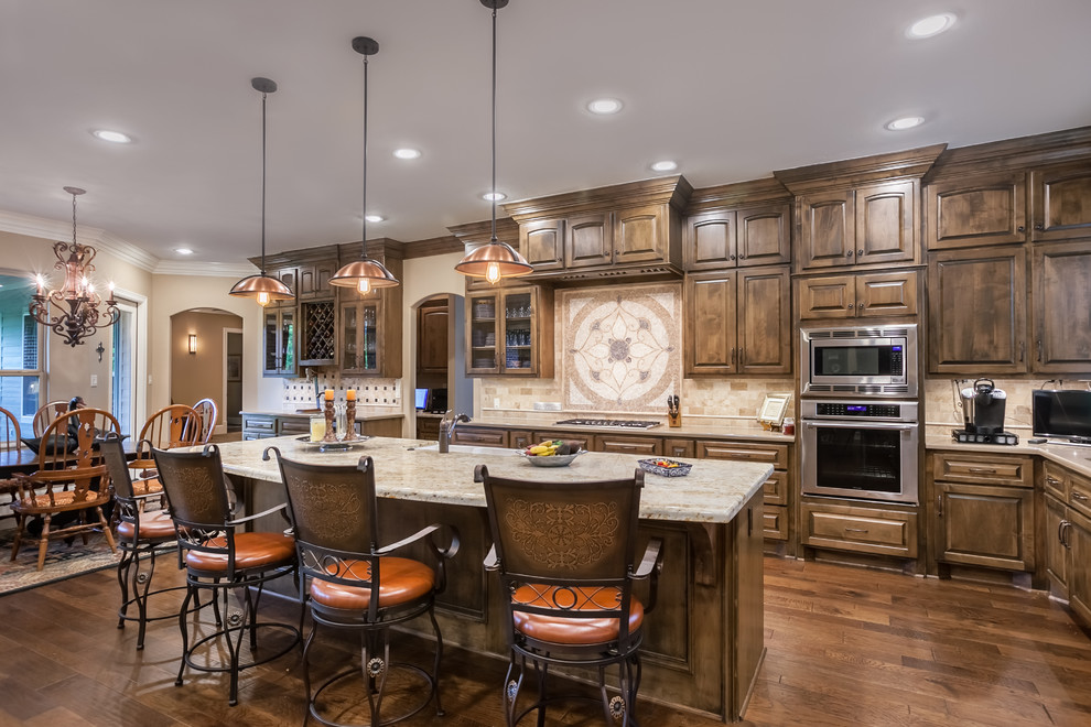 Design ideas for a country l-shaped eat-in kitchen in Houston with a farmhouse sink, raised-panel cabinets, medium wood cabinets, beige splashback, stainless steel appliances, medium hardwood floors and with island.