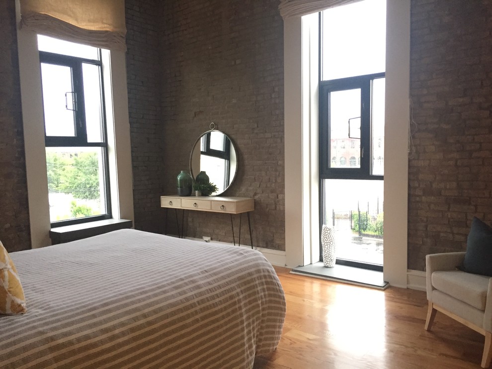 Photo of an industrial loft-style bedroom in Louisville with medium hardwood floors and no fireplace.