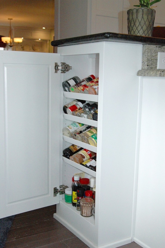 Example of a mid-sized transitional l-shaped medium tone wood floor and brown floor enclosed kitchen design in Boston with an undermount sink, recessed-panel cabinets, white cabinets, granite countertops, multicolored backsplash, glass tile backsplash, stainless steel appliances and an island