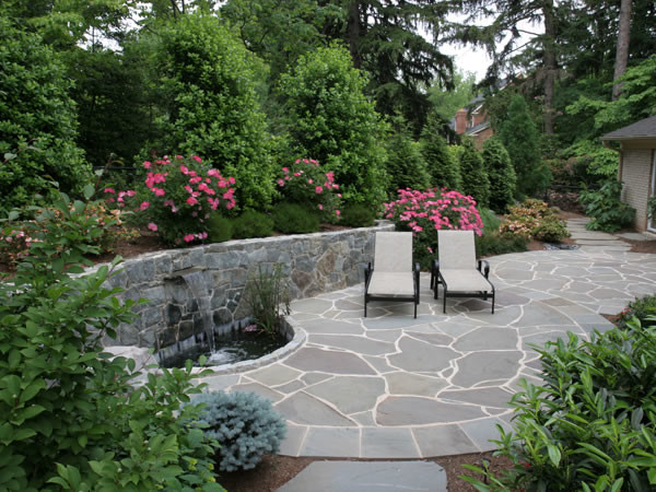 This is an example of a mid-sized contemporary backyard patio in DC Metro with natural stone pavers, a water feature and no cover.