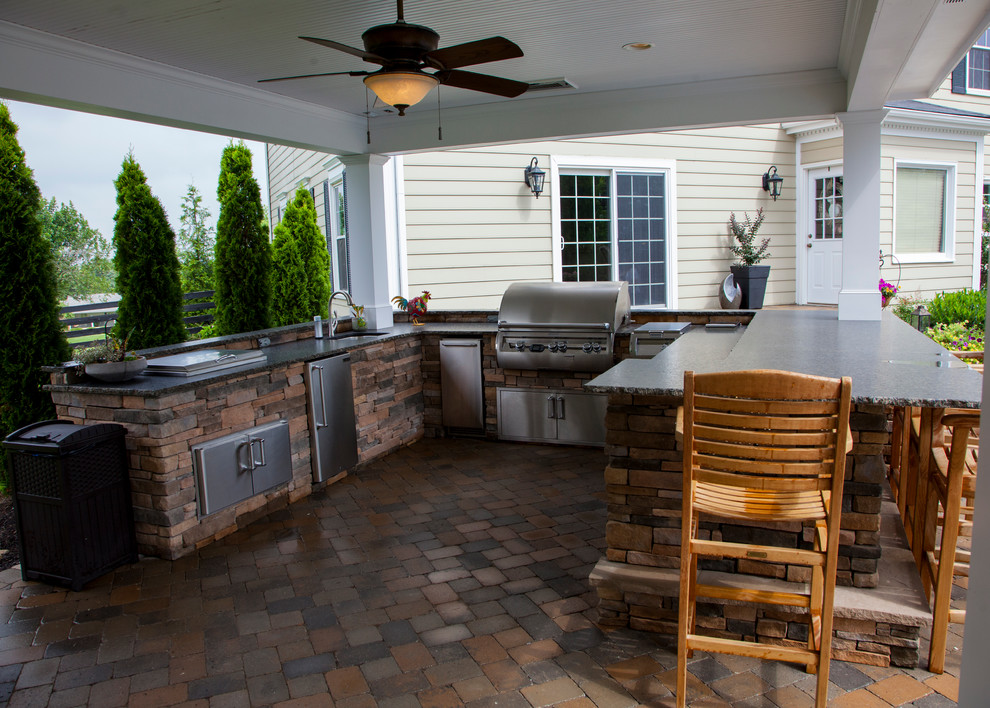 Example of a large classic backyard stone patio kitchen design in Orange County with a gazebo