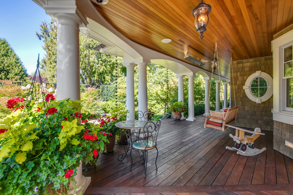 Large victorian front veranda in Seattle with with columns, decking and a roof extension.
