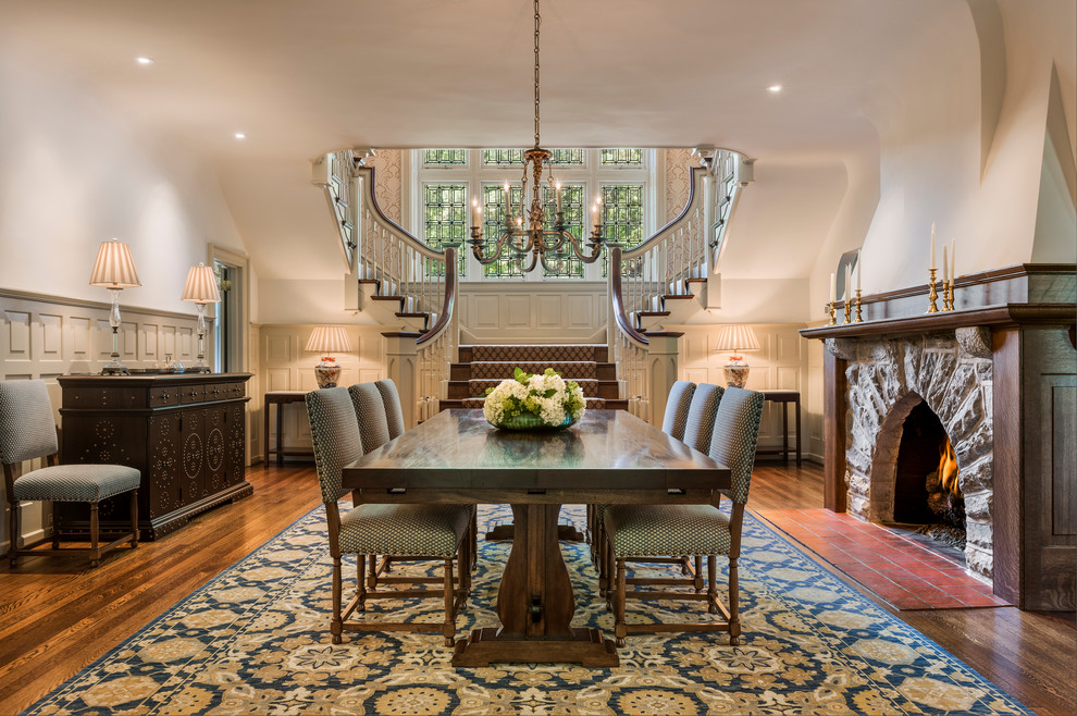 This is an example of a traditional dining room in Philadelphia with white walls, a standard fireplace, a stone fireplace surround and dark hardwood floors.